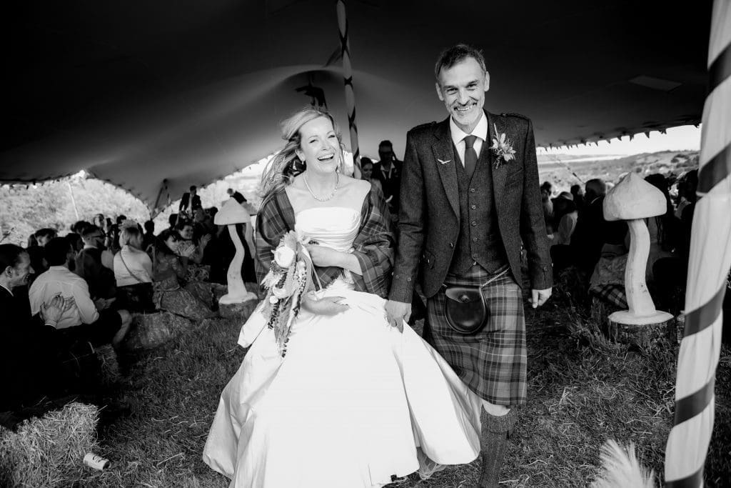 Alternative wedding couple walking down grassy aisle after tying the knot at Marthrown of Mabie